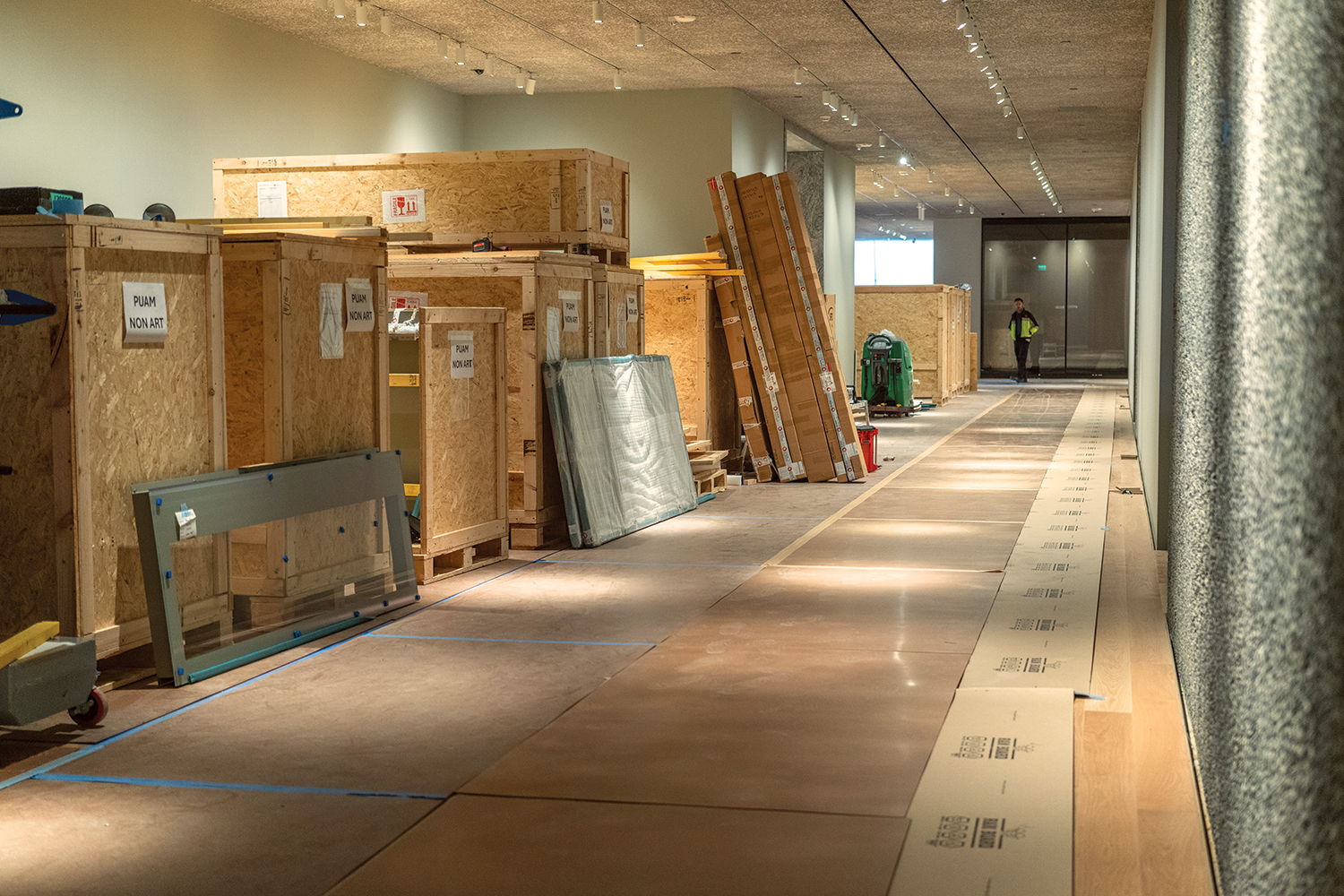 A hallway is lined on one side with wooden crates.