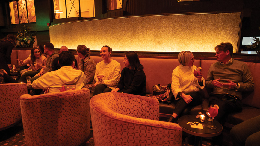People sitting in a modern and sleek dark dining room enjoying food and drinks