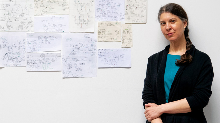 Dr. Chloe Atreya ’98 stands against a wall covered in complex diagrams