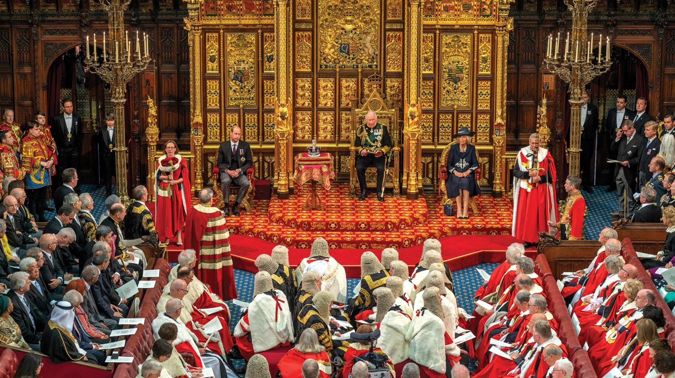 Members of the Lords, and judges, ambassadors, high commissioners, and guests listen to a speech in the House of Lords chamber.