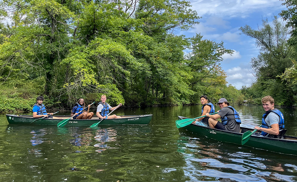20240831_OutdoorAction_WA430_IMG_3761.jpg Two canoes, each with three student paddlers, navigate on a creek