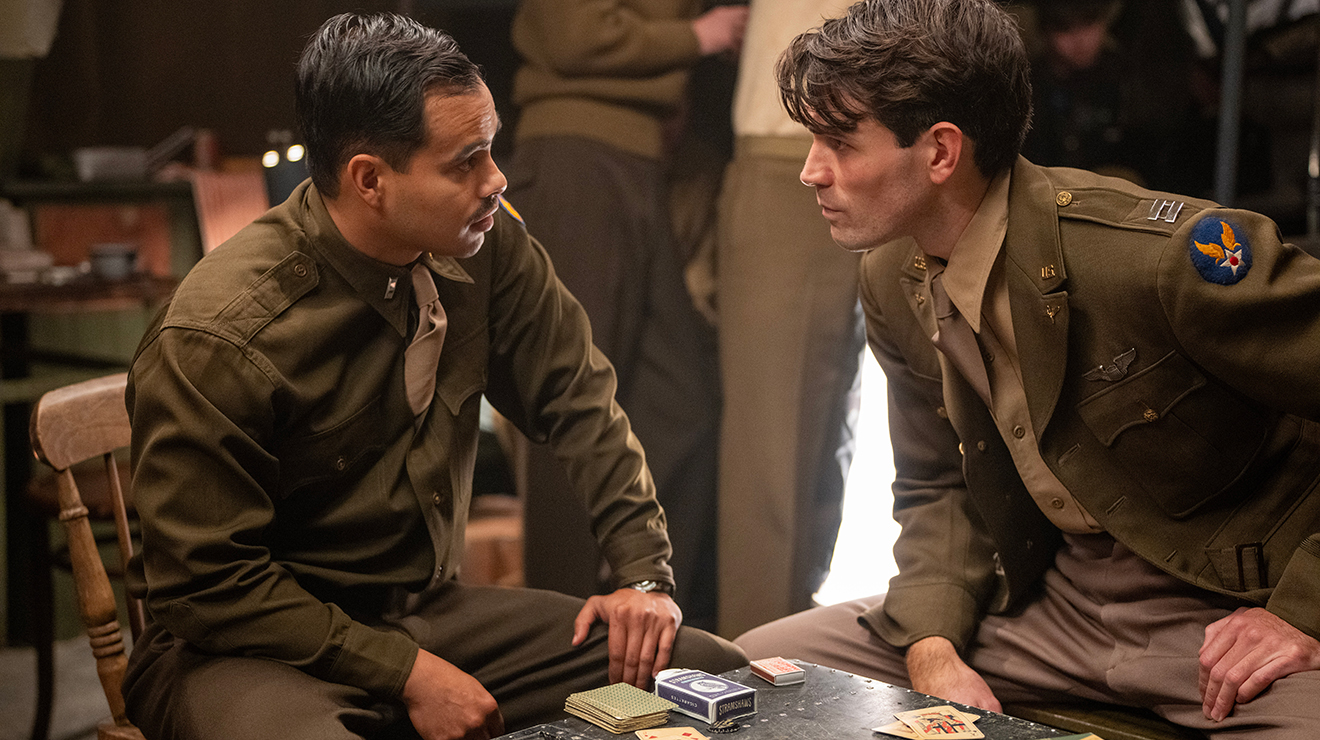 KJ Apa as Captain Jimmy Stewart and Julian Works as Lieutenant Martinez in the upcoming major motion picture JIMMY. Photo courtesy of Burns & Co., © 2026 JIMMY The Movie LLC, All Rights Reserved_.jpg Two men in World War II Army uniforms talk over a table with cards and dice on it.