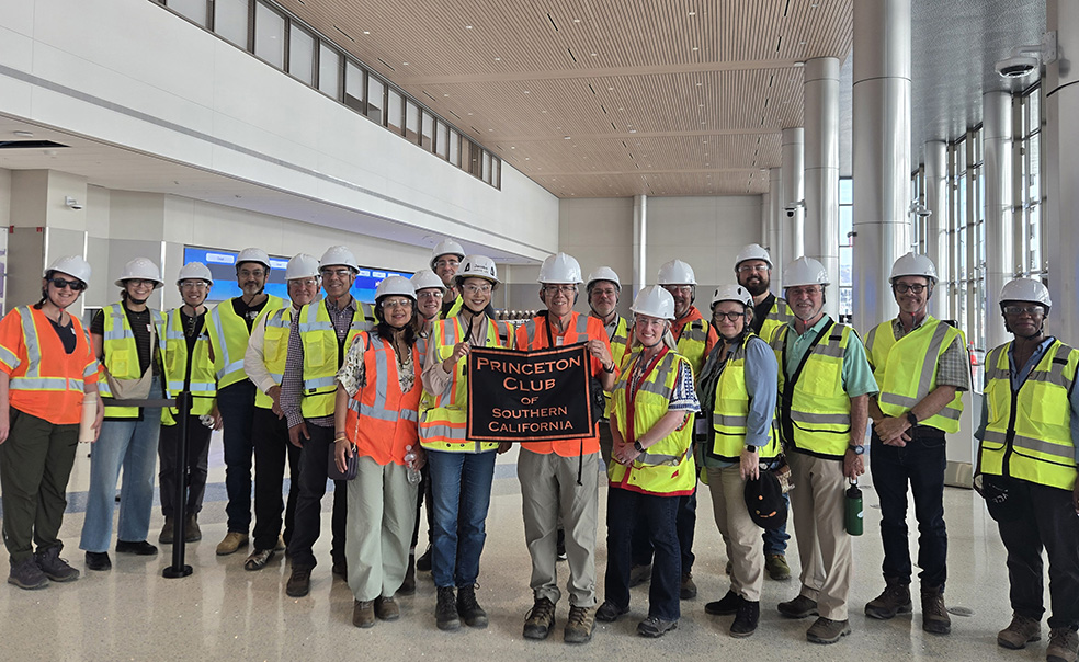 TOW_JaniceLee_PrincetonClub_Burbank1.jpg About 20 people in florescent vests and hard hats stand in an airport and hold a sign that says "Princeton Club of Southern California."