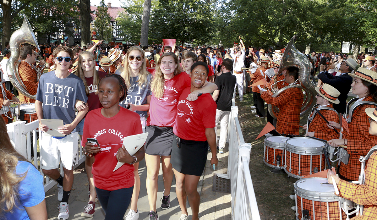Students walking in the Pre-rade in on the front campus with band members alongside the path