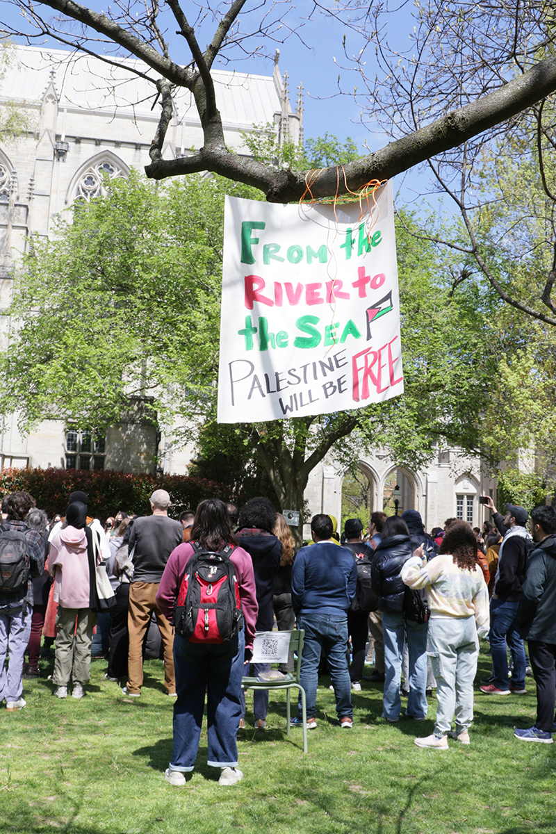 Bev1_rivertosea_cropped.jpg People stand under a banner hung in a tree in McCosh Courtyard reads, “From the River to the Sea, Palestine will be free.”