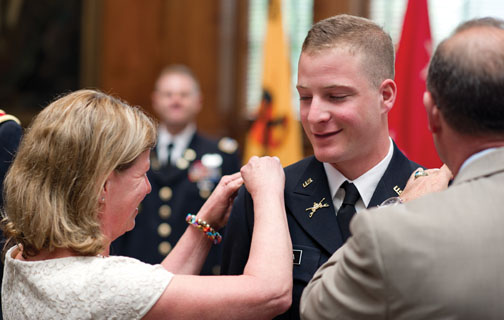 The parents of Greg Colella &rsquo;12 proudly pin epaulettes on the uniform of their son, a second lieutenant.