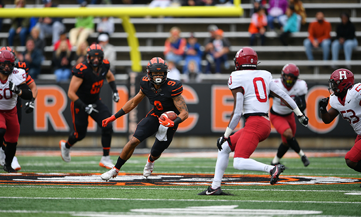 Wide receiver Andrei Iosivas ’23 runs with the ball, dodging Harvard players.