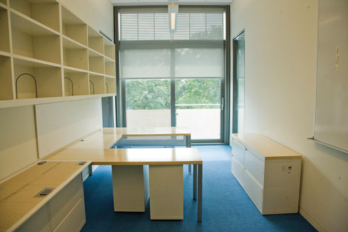 A senior-faculty office reflects modern styling; sliding-glass doors open onto an exterior ­“balconette.”