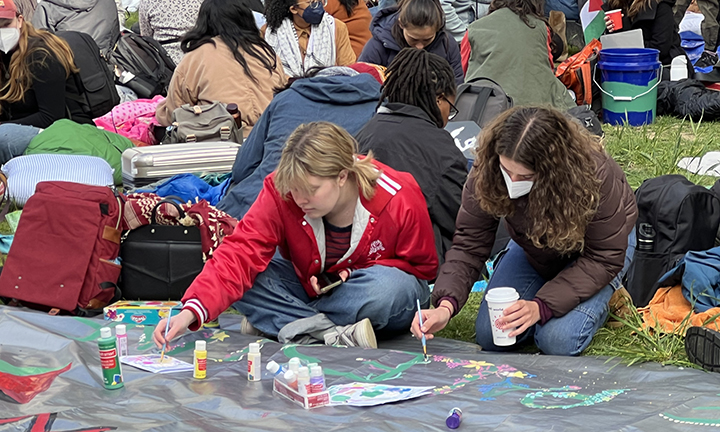 Protest5.jpg Two women paint a banner on the ground.