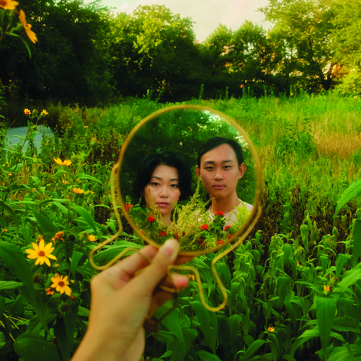 Two people in a field, reflected in a round mirror.