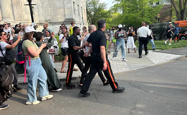 ProtestCourtHearing.jpg Public Safety police officers walk a man in handcuffs the night in April when student protestors staged a sit-in at Clio.
