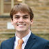 James Swineheart in dark blue suit with orange tie in front of Nassau Hall