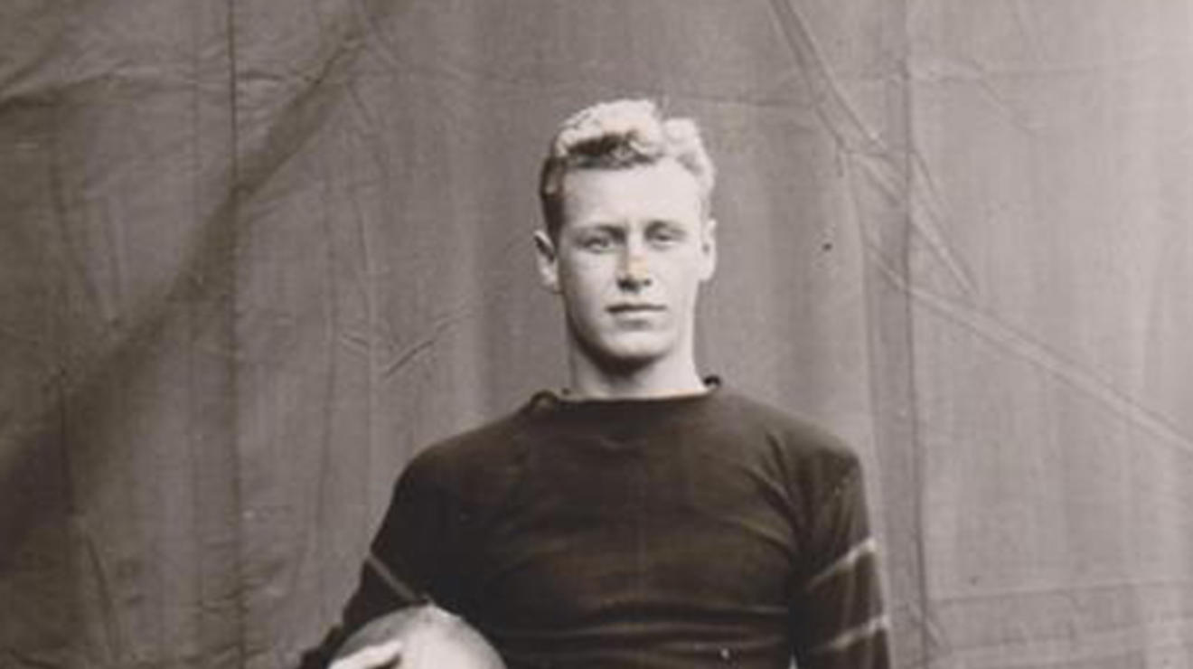 Black and white photo of Hobey Baker holding a football. 