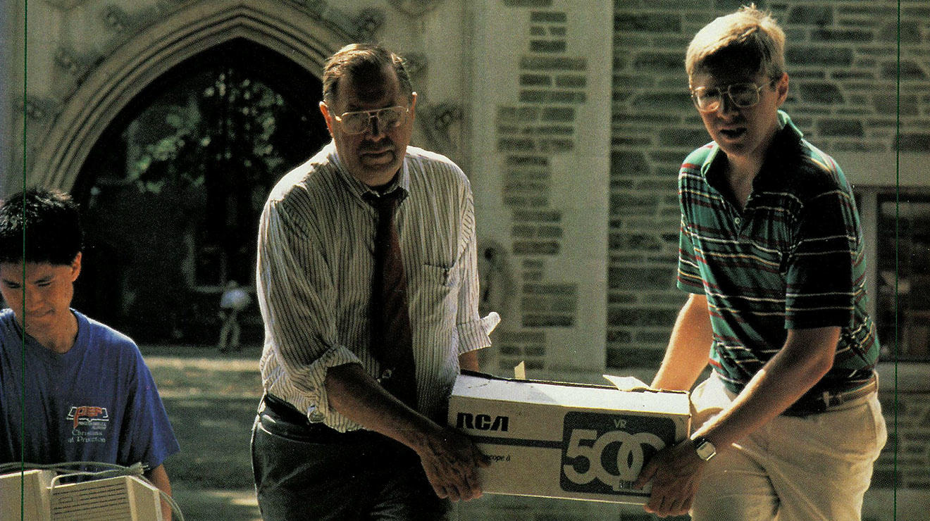 Father and son carry a VCR to the son's dormitory