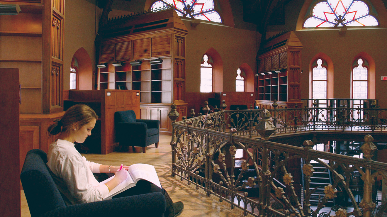 Student in chair studying on the balcony of Chancellor Green building