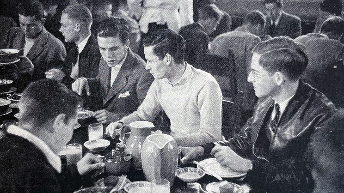 Several students eating at a dining hall table, circa 1950s or 1960s