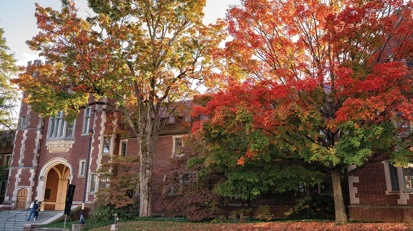 OTC_FallCampus_100924_0014.jpg Trees turn red, yellow, and orange in front of a Gothic brick building.