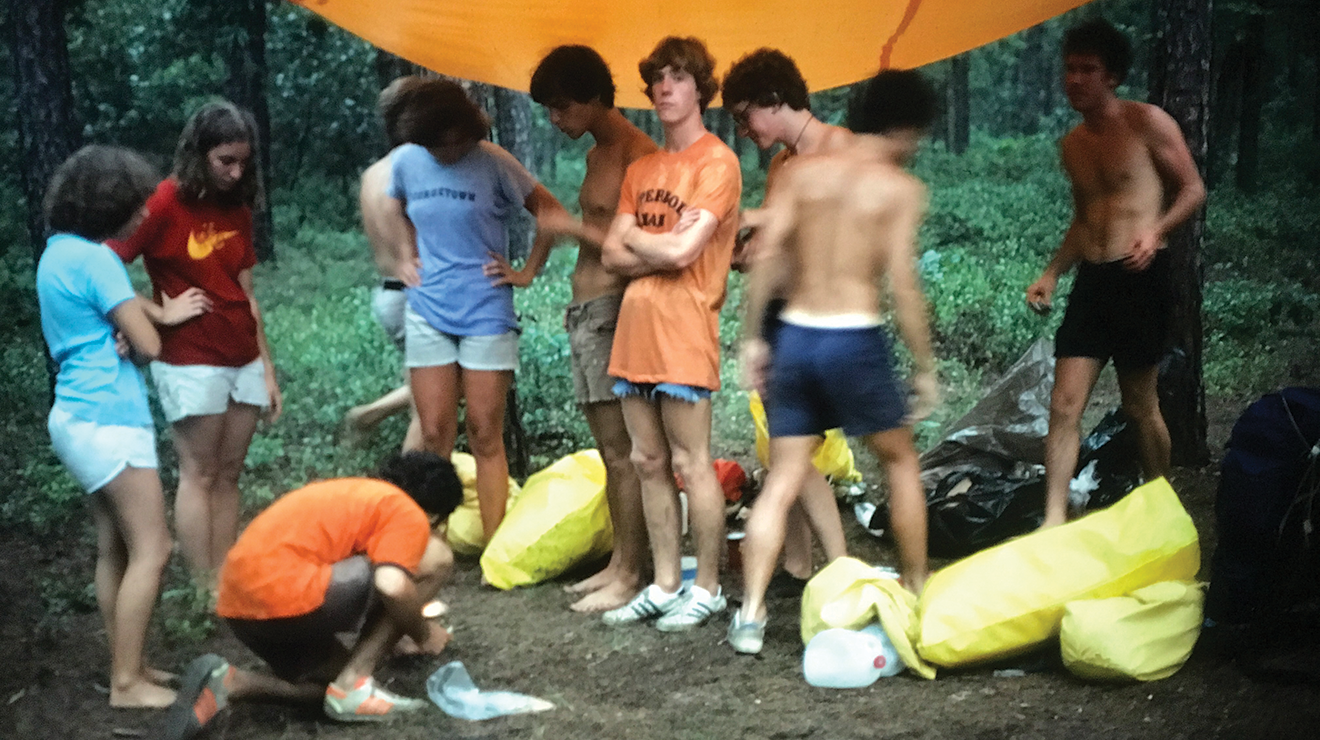 A group of hikers gathered under a tarp