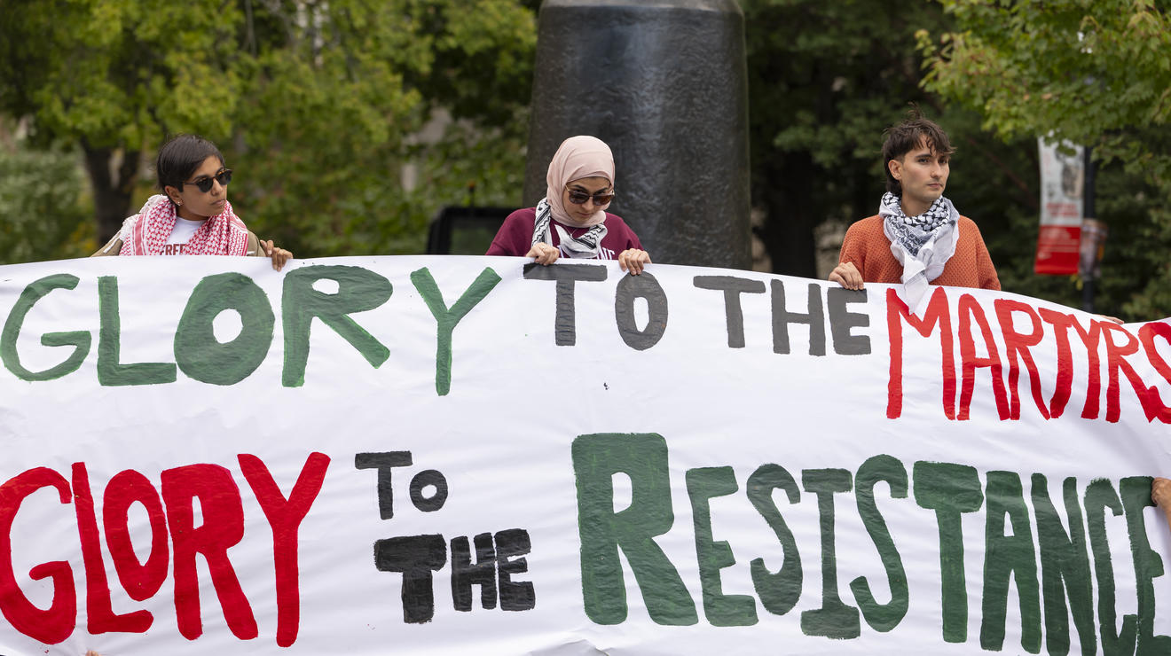 Pro-Palestinian activists hold a sign in Firestone Plaza. The sign they are holding reads "Glory to the Martyrs Glory to the Resistance."