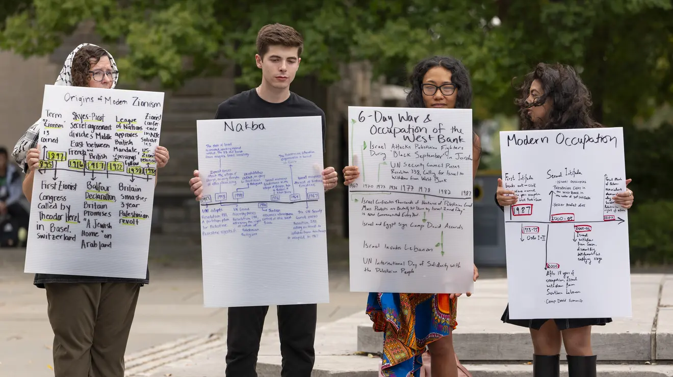 Pro-Palestinian activists holding signs outside in Firestone Plaza
