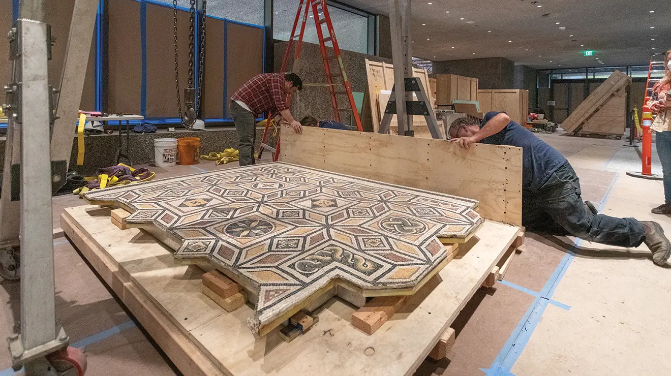 ART MUSEUM_carousel1.jpg Two men work on a wood platform holding a Roman floor mosaic.