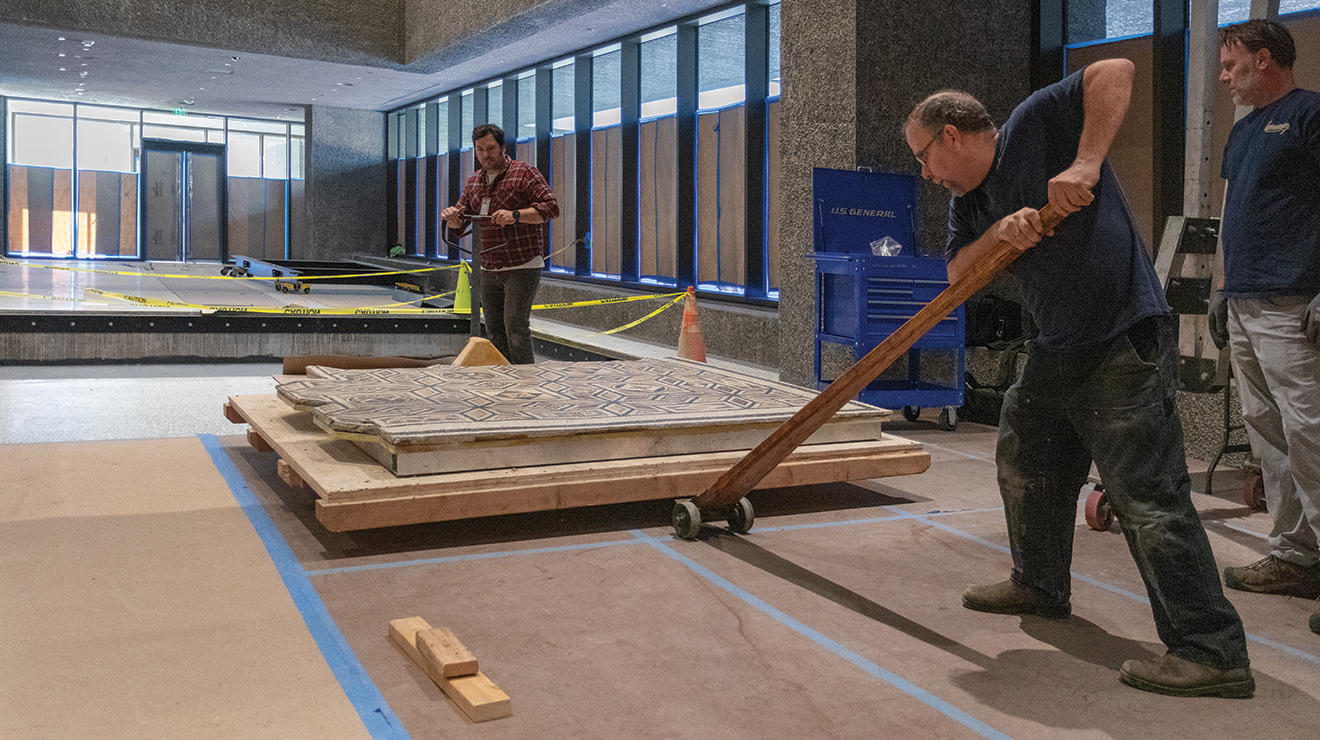 Two men work on installing a Roman floor mosaic.