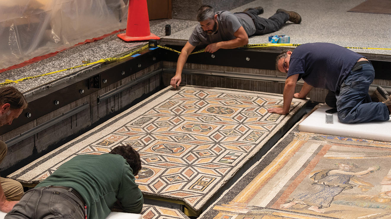 Three men work on installing a Roman floor mosaic.