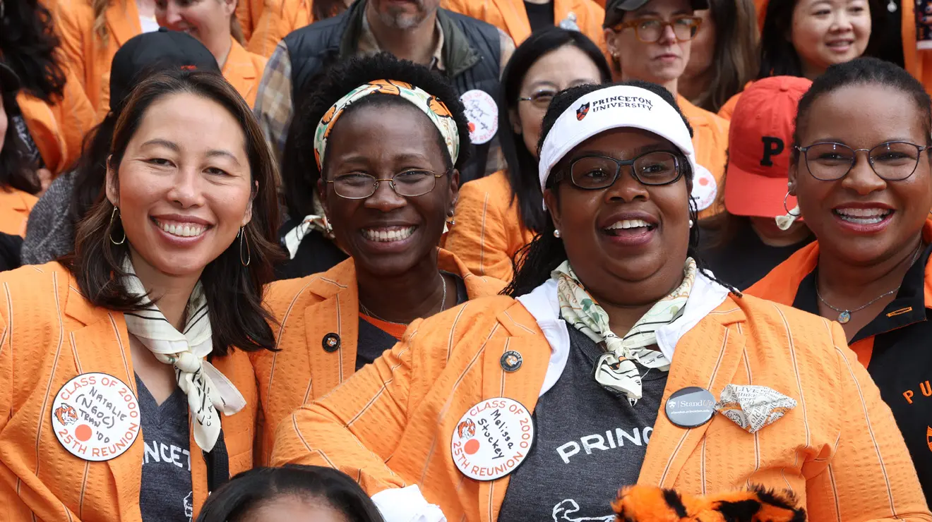 Four women from the Class of 2000 smile on the Blair Arch steps getting their class picture taken.