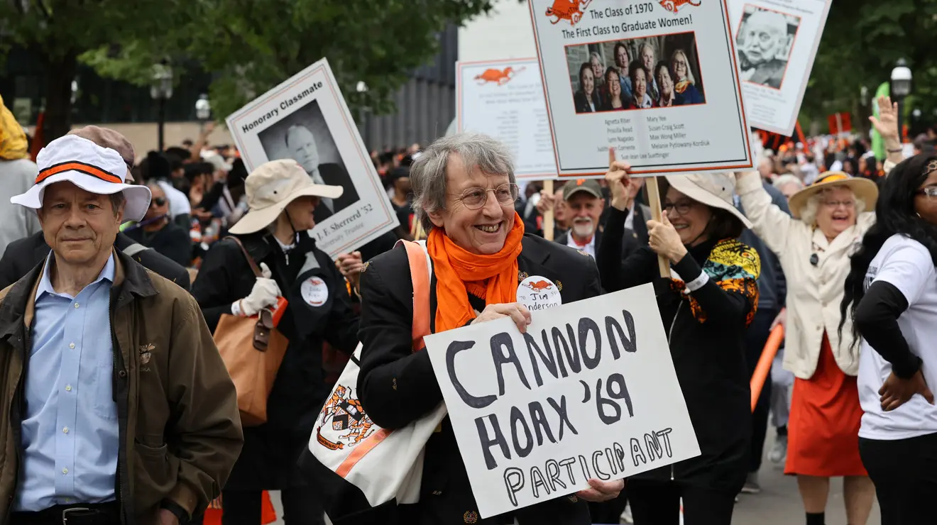Jim Anderson of the Class of 1970 holds a handwritten sign during the P-rade saying "Cannon Hoax 1969 Participant."