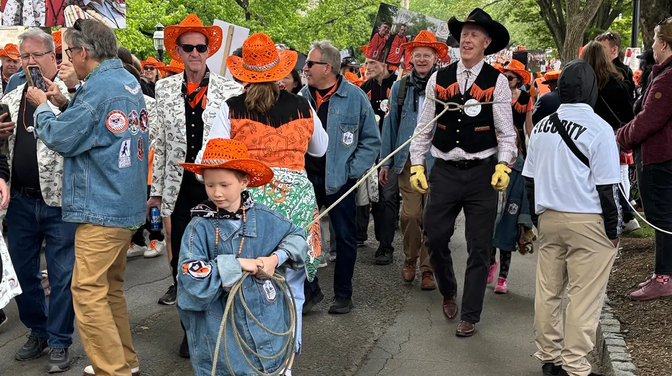 A boy wearing an orange cowboy hat pulls a man with a rope in the 2025 P-rade.