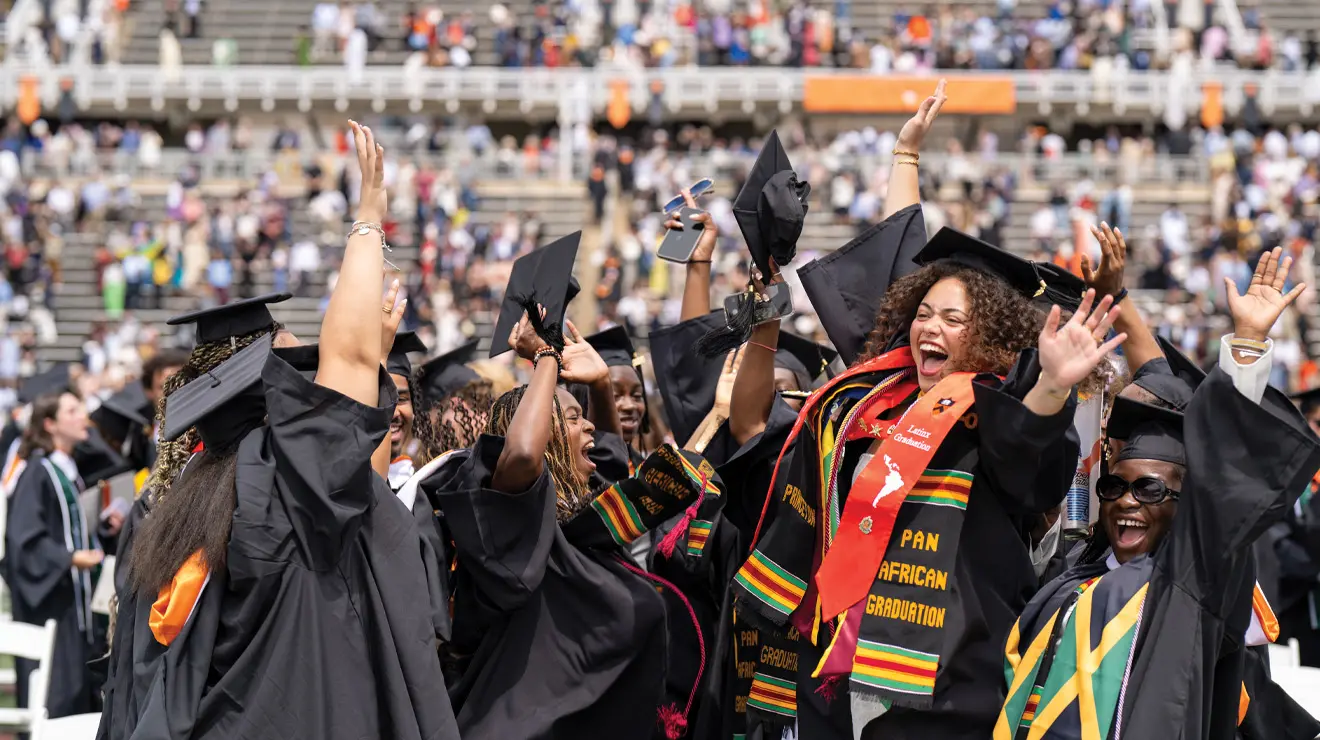 A group of graduates jump with joy at Commencement