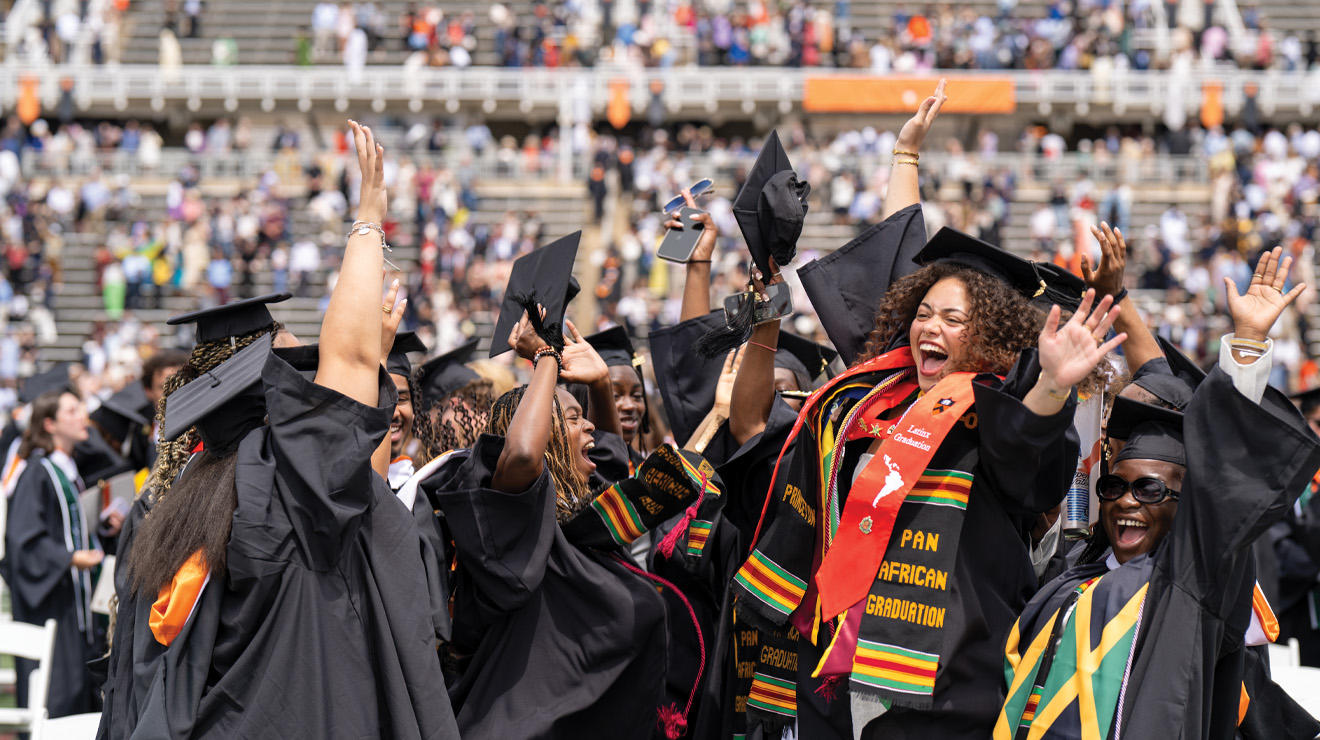 A group of graduates jump with joy at Commencement