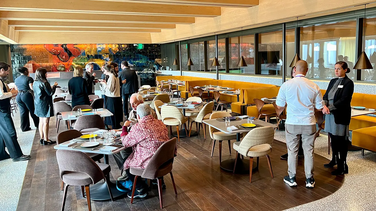 ARTMUSEUM_Mosaic_inside.jpg People sit and stand in an indoor restaurant.