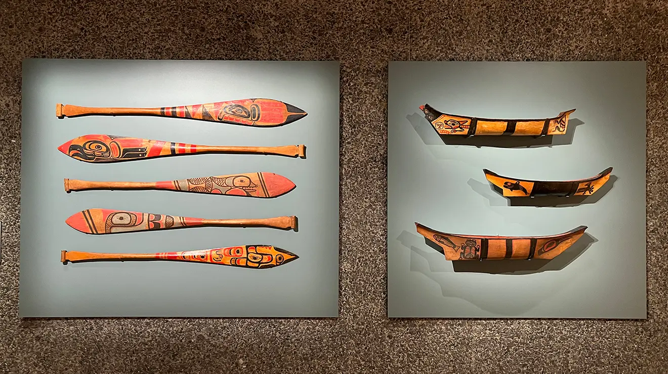 ARTMUSEUM_Polynesian_oars.jpg Indigenous carved and painted paddles and model canoes are arranged on a wall.