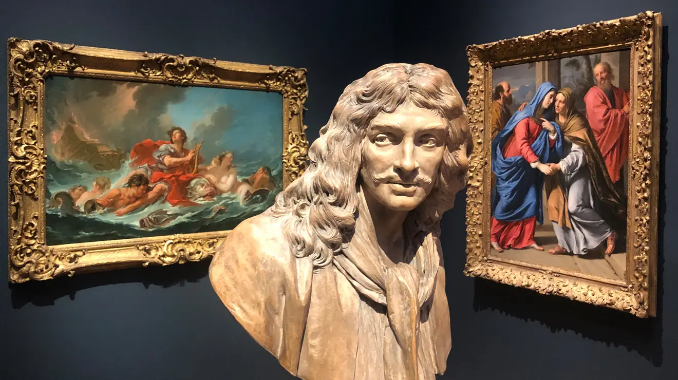 ART_Jean Antoine Houdon_Jean-Baptiste Poquelin.jpg A bust statue of a man with long hair is placed in front of two paintings.