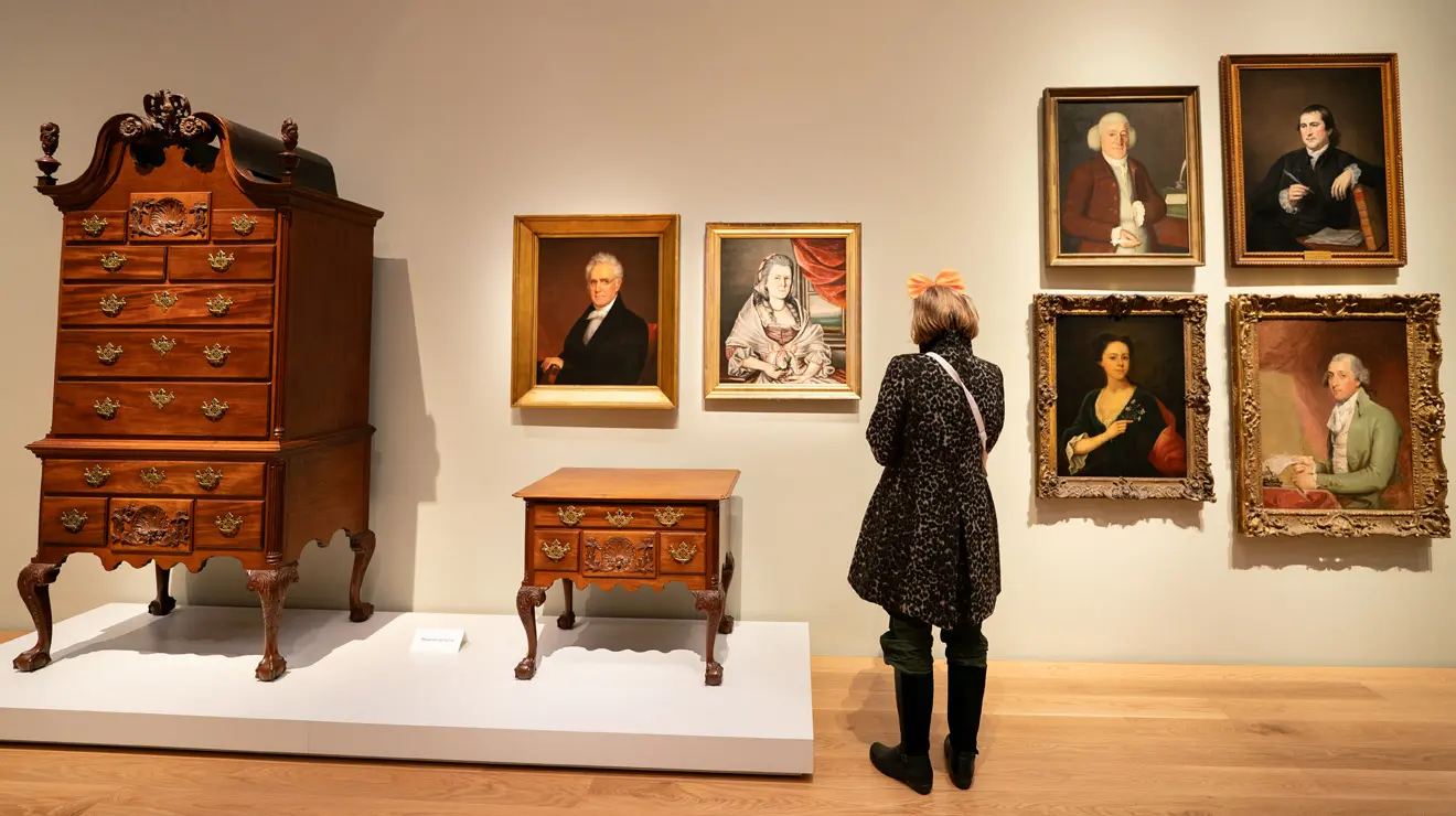 PAUM OPENING_Colonial America.jpg A woman looks over colonial-era art including paintings and furniture at the Princeton University Art Museum.