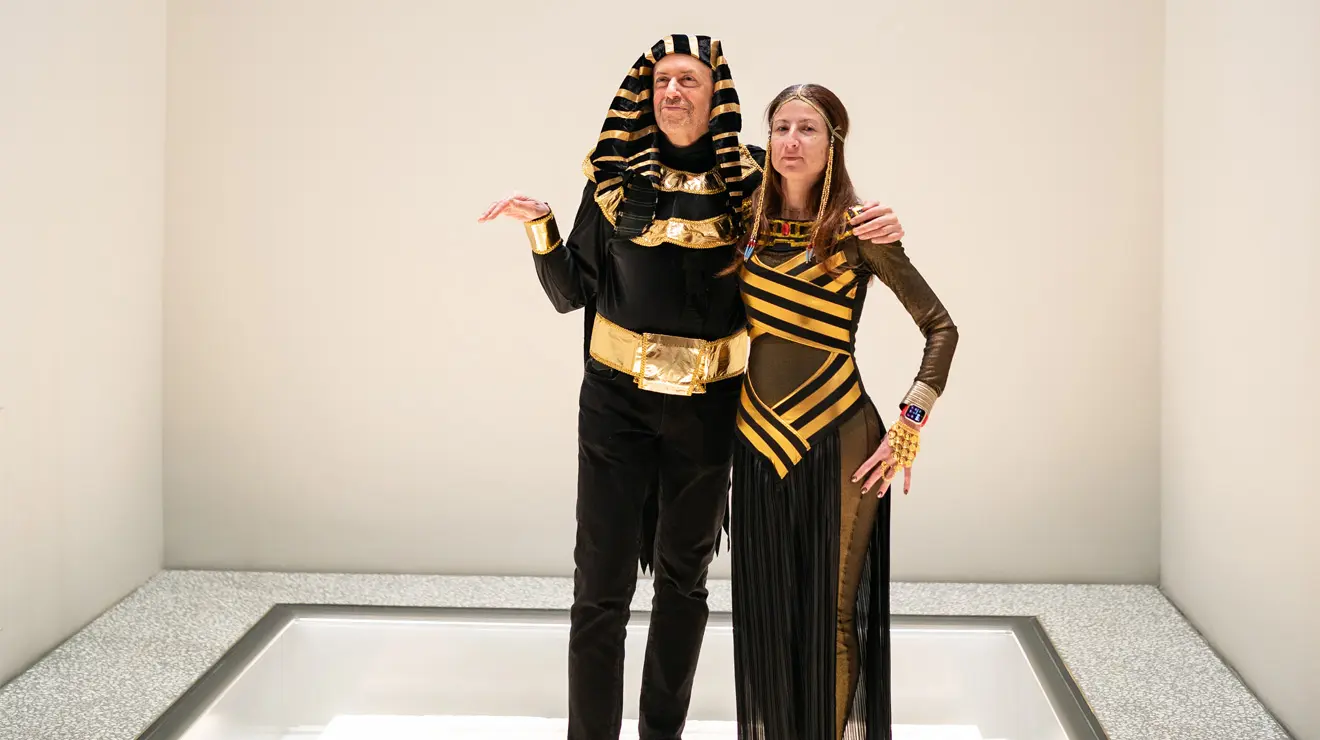 PAUM OPENING_Mr and Mrs Tutt.jpg Man and woman dressed as Egyptian pharaohs stand in a white room.