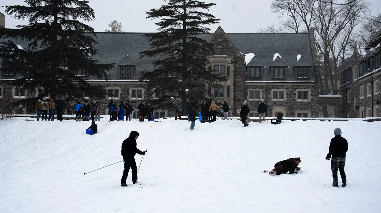 Students play in the snow; one cross country skis.