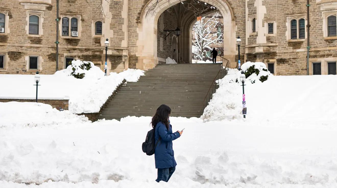 Student in blue coat walks past Blair Arch after the blizzard.