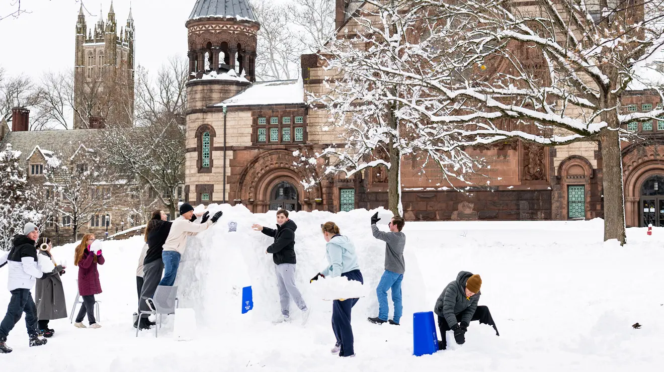 Students build a snow structure behind Alexander Hall