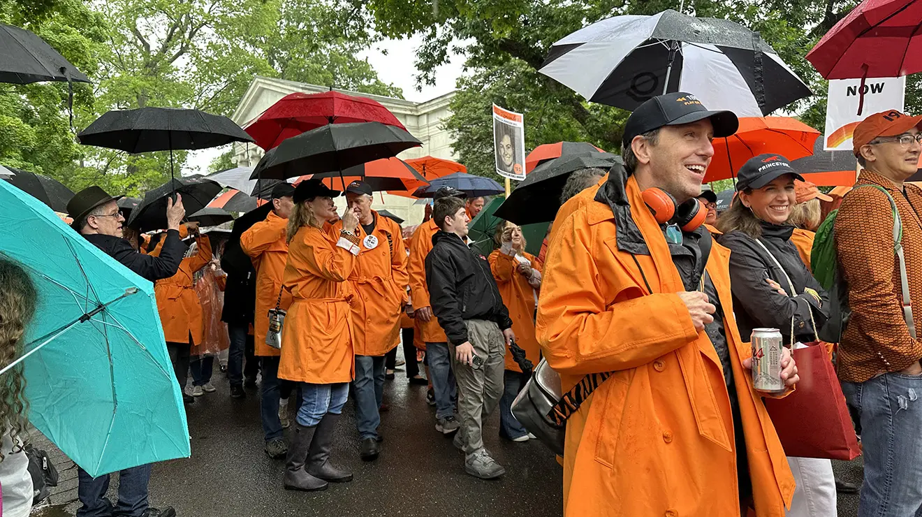 People wearing orange rain jackets hold umbrellas and march in the 2026 P-rade.