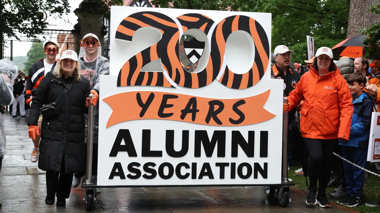 People carry a sign in the P-rade reading "200 Years Alumni Association."