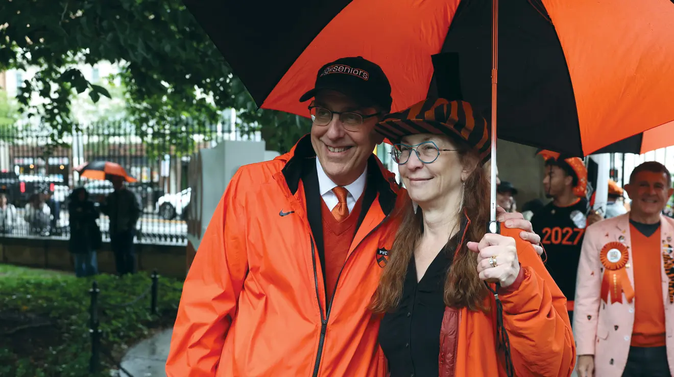 President Eisgruber and a woman under a black and orange umbrella.