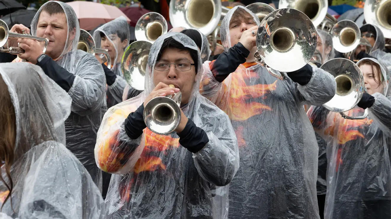 A guy in a clear poncho plays a trumpet.