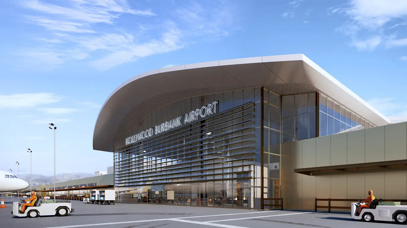 TOW_JaniceLee_BurbankAirport5.jpg A rendering of the outside of an airport, with a curved roof and glass all along the side; the nose of an airplane peeks out on the left of the outdoor area.