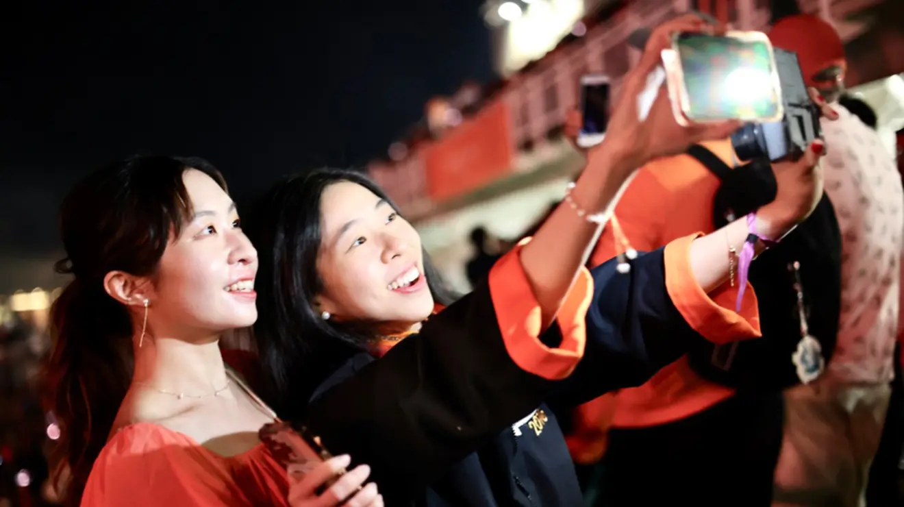 Two women take a selfie at night outdoors.