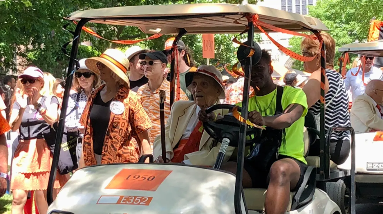 A student drives a member of the Old Guard in a golf cart.