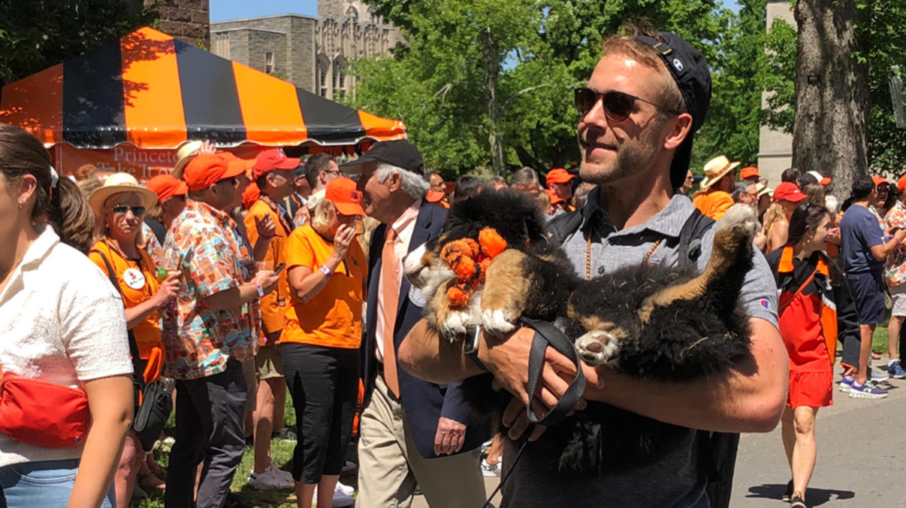 A man carries a dog in the P-rade.