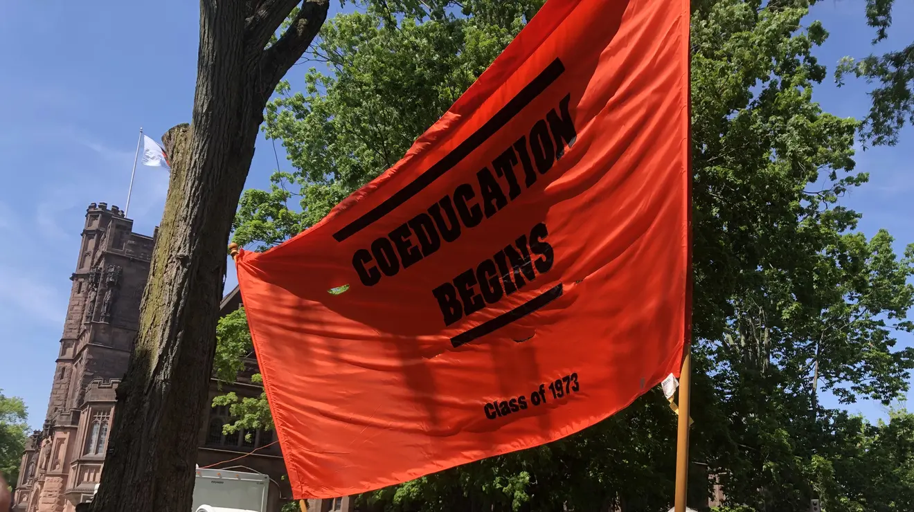 The Class of 1973 holds a large banner reading, “COEDUCATION BEGINS.”