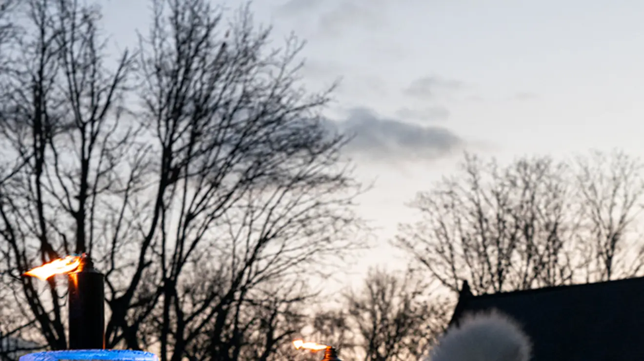 A view of the ice menorah showing it's about as tall as the person standing beside it in a winter hat.